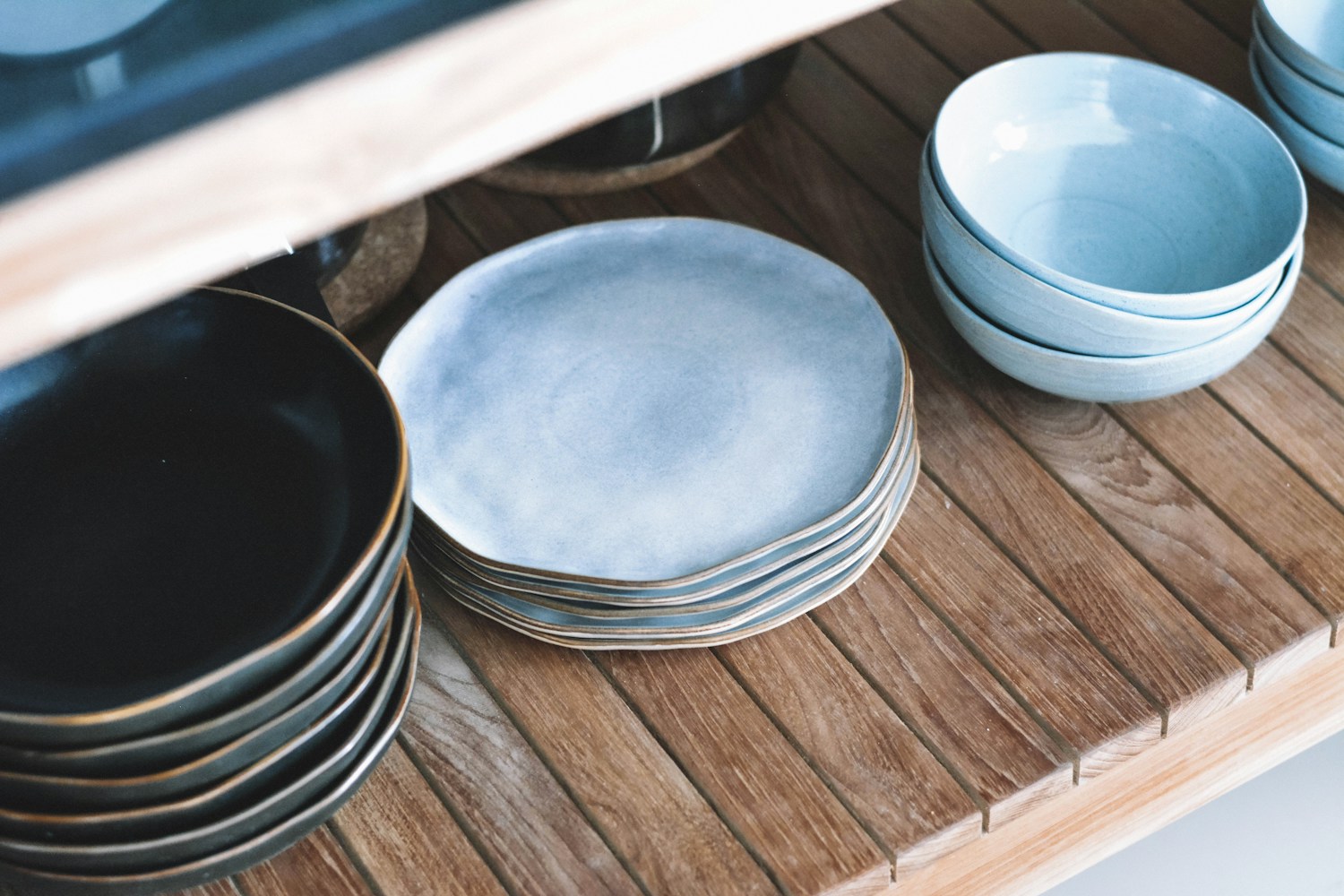 Vajilla cerámica en tonos naturales dispuesta sobre una mesa de madera